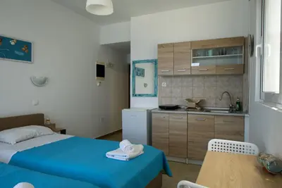 a small bedroom with a blue bed and a kitchen at Lilian's Seaview-Party Street-Youth Studios in Rhodes Town