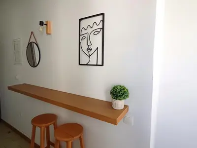 a wall with a wooden shelf and two stools at Lilian's Seaview-Party Street-Youth Studios in Rhodes Town