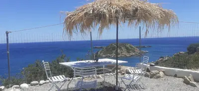a table and chairs under a straw umbrella at Casa di Mare Stegna in Archangelos