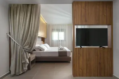 a bedroom with a bed and a flat screen tv at Lardos Luxury Apartments in Lardos