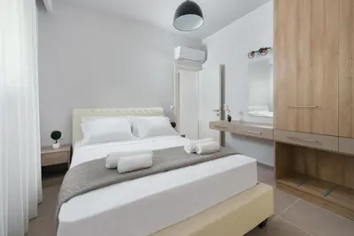 a white bedroom with a large bed and a bathroom at Lardos Luxury Apartments in Lardos