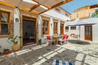 a patio with a table and chairs and an umbrella at The Grandma House in Ialyssos