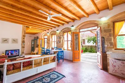 a living room with wooden ceilings and a fireplace at The Grandma House in Ialyssos