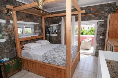 a bedroom with a canopy bed in a room with stone walls at Pefkos Eye in Pefki Rhodes