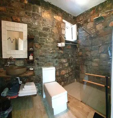 a stone bathroom with a toilet and a sink at Pefkos Eye in Pefki Rhodes