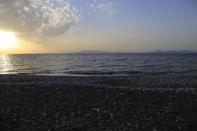 a beach with the sun setting over the water at M&B Luxury House in Theologos