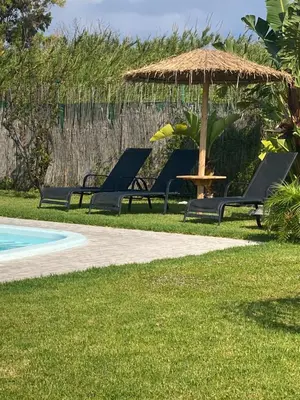 a group of chairs and an umbrella next to a pool at M&B Luxury House in Theologos