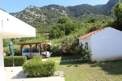 a house with a car parked in a yard with mountains at Salakos Mountain View Home in Sálakos