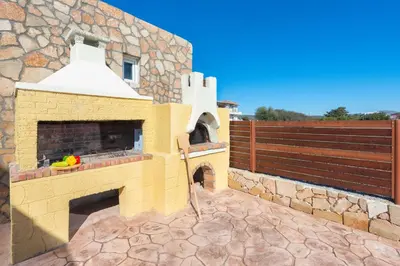 a brick pizza oven on a patio with a fence at MarySol Luxury Villa in Gennadi