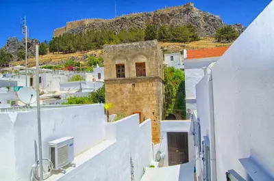 a group of white buildings with a mountain in the background at Lindos Tholos Villa in Líndos