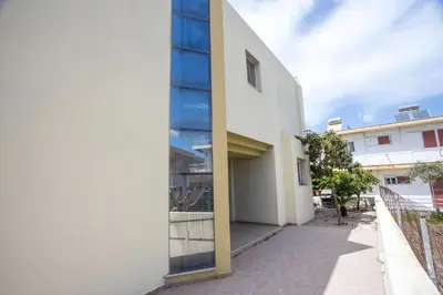 a white building with blue panels on the side of it at EVA's House in Pastida
