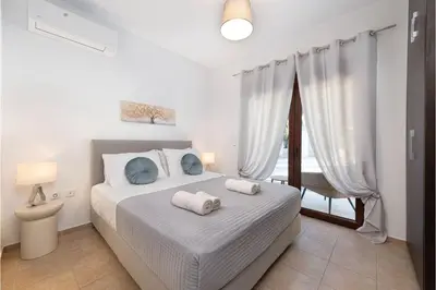 a white bedroom with a bed and a window at Villa Leyland in Faliraki
