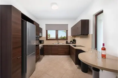 a kitchen with a stainless steel refrigerator and a table at Villa Leyland in Faliraki