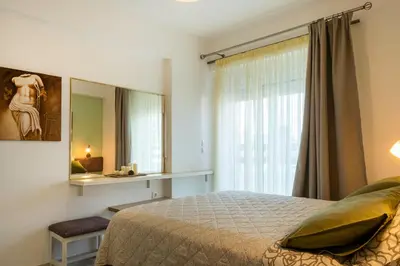 a bedroom with a bed and a mirror and a window at Green Apartments in Faliraki