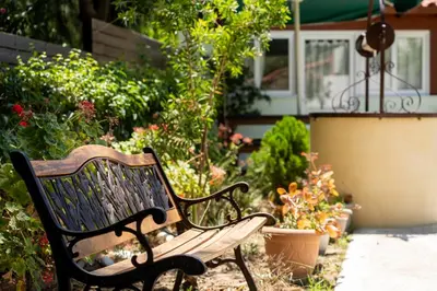 a bench in a garden with flowers and plants at Green Apartments in Faliraki