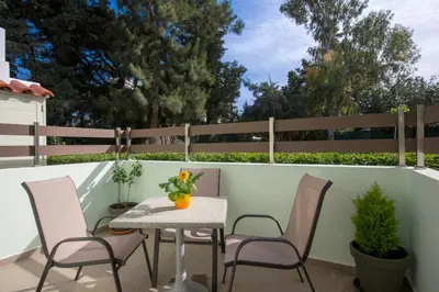 a patio with a table and chairs and a fence at Green Apartments in Faliraki