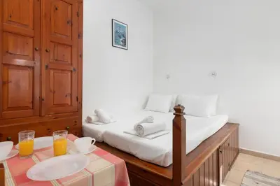 a bedroom with a bed and a table with two glasses of orange juice at Apostolos Rooms in Líndos
