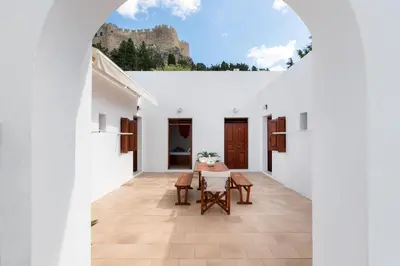 a view from the hallway of a white house with a table and chairs at Apostolos Rooms in Líndos