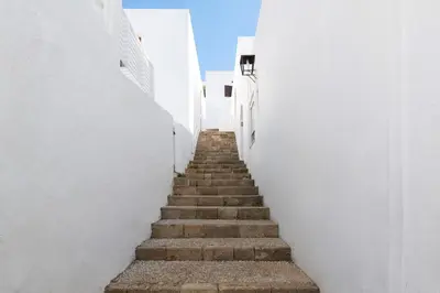 a stairway with white walls and white stairs at Apostolos Rooms in Líndos