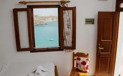 a window with a view of a boat in the water at Apostolos Rooms in Líndos