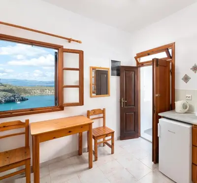 a kitchen with a table and a window at Apostolos Rooms in Líndos