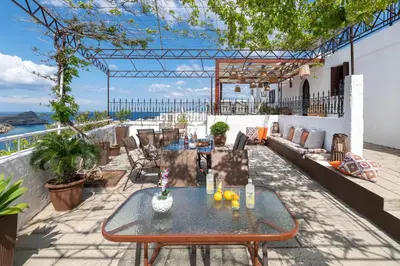a table on a patio with a view of the ocean at Apostolos Rooms in Líndos