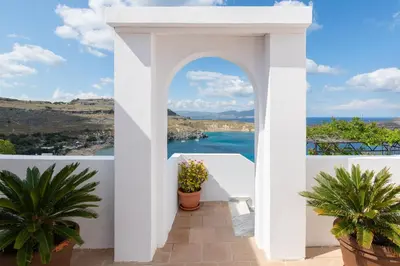 a white archway with potted plants and the ocean at Apostolos Rooms in Líndos