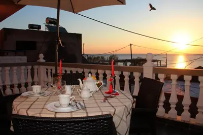 a table on a balcony with the sunset in the background at Dimitras Luxus House in Archangelos