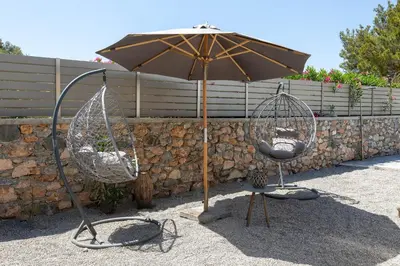 an umbrella and two swings in front of a wall at Villa Bella with Private Pool and Hot Tub in Lardos