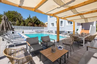a patio with a table and chairs and a swimming pool at Villa Bella with Private Pool and Hot Tub in Lardos