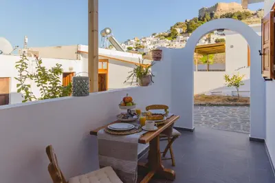 a table and chairs on the balcony of a house at Lindos SeaStar Apartment in Líndos
