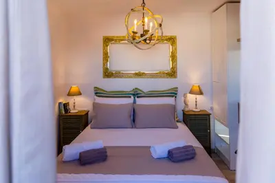 a bedroom with a bed with a mirror and two lamps at Lindos SeaStar Apartment in Líndos