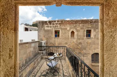 a balcony of a building with a table and a chair at Captains House in Líndos