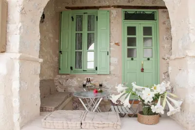 a patio with a table and a green door at Villa Klytia in Halki
