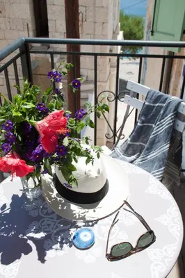 a table with a hat and flowers on a balcony at Villa Klytia in Halki