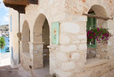 a stone building with a door and flowers on it at Villa Klytia in Halki