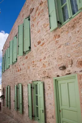 a brick building with green shuttered windows at Villa Klytia in Halki