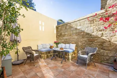 a patio with chairs and a table and a brick wall at Maison Roxanne & Maisonette in medieval city by Rhodes4vacation in Rhodes Town