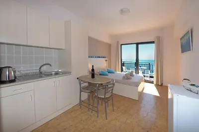 a kitchen and living room with a bed and a table at Horizon View Studio in Haraki