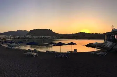 a beach with chairs and umbrellas at sunset at Horizon View Studio in Haraki