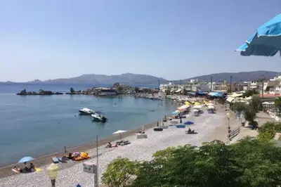 a beach with people and boats in the water at Horizon View Studio in Haraki
