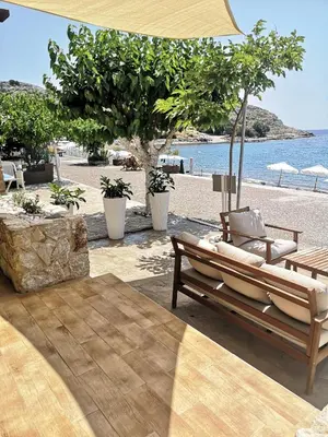 a beach with a couple of chairs and an umbrella at Relax Seaside House by living in blue in Haraki