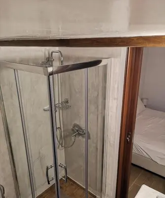 a shower stall in a room with a bed at Relax Seaside House by living in blue in Haraki