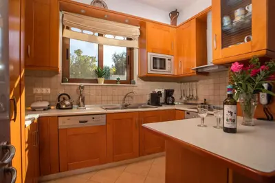 a kitchen with wooden cabinets and a counter top at Christine Villa Pefkos in Pefki Rhodes