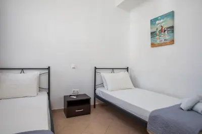 a room with two beds and a night stand at Christine Villa Pefkos in Pefki Rhodes