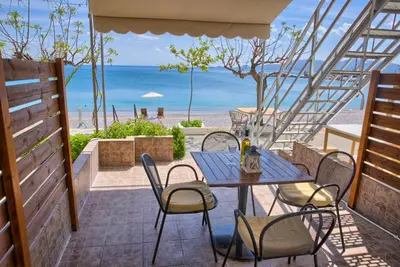 a patio with a table and chairs and the beach at Haraki Dream View in Haraki