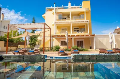 a hotel with a swimming pool in front of a building at Kallithea Breeze Luxury Villa in Koskinou