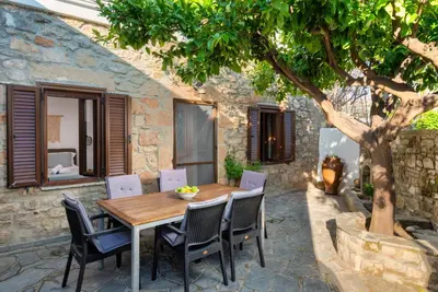 a wooden table and chairs under a tree on a patio at Villa Claudia in Lardos in Lardos