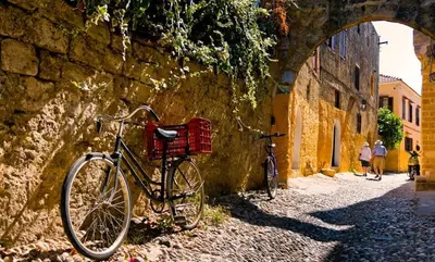 a bike with a basket parked against a stone wall at Praxitelous 9 Old Town in Rhodes Town