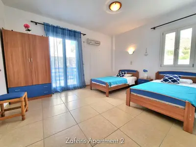 a bedroom with two beds and two chairs at Zafeiris Apartments in Livadia